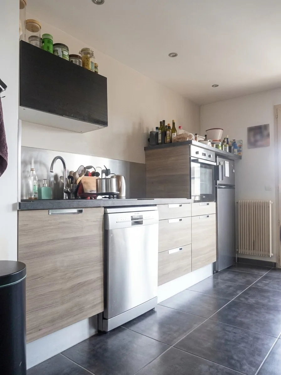 Après la transformation : la même cuisine nette, façades bois, électroménager inox et carrelage détaillés