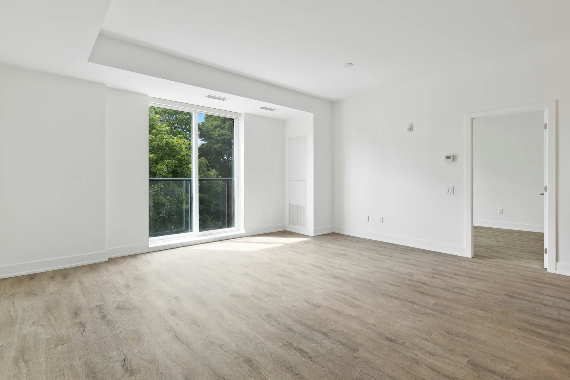 Séjour livré nu, murs blancs et parquet sans mobilier : aucun repère d'échelle pour l'acquéreur