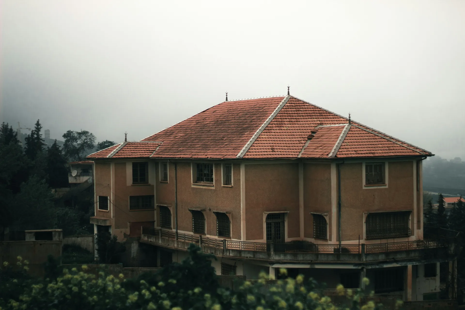 Villa aux tuiles rouges sous la brume, ciel gris uniforme